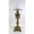 A Victorian brass paraffin lamp, with brass reservoir on a cast floral column, clear glass chimney a... 