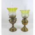 Two Victorian brass paraffin lamps, each with a brass reservoir on circular base, clear glass chimne... 