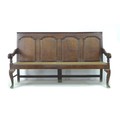 An 18th century oak settle, with four panelled back rest, moulded armrests, resting upon three back ... 