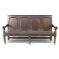 An 18th century oak settle, with four panelled back rest, moulded arm rests, turned supports, and th... 