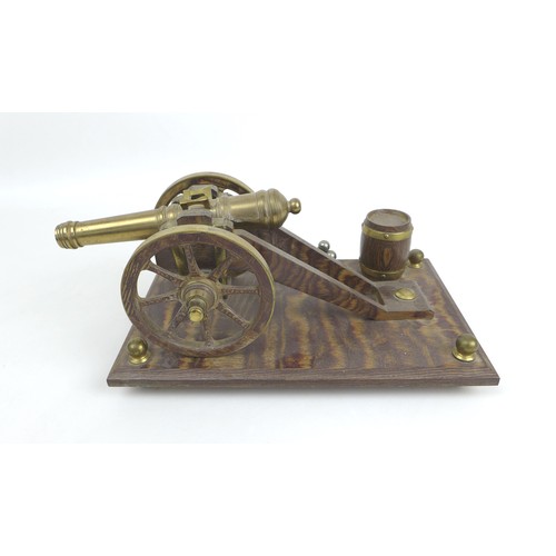 63 - A mid 20th century brass and oak model canon on stand, overall 31 by 17 by 13cm high.