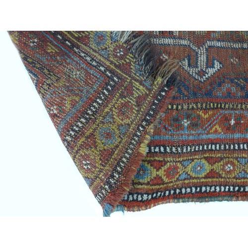 172 - Two hand knotted woolen rugs, one with a dark blue ground and an orange geometric design with white ... 