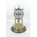 A Kundo torsion clock, on a brass effect circular base, with glass dome, dial 9cm, 19 by 30cm high o... 