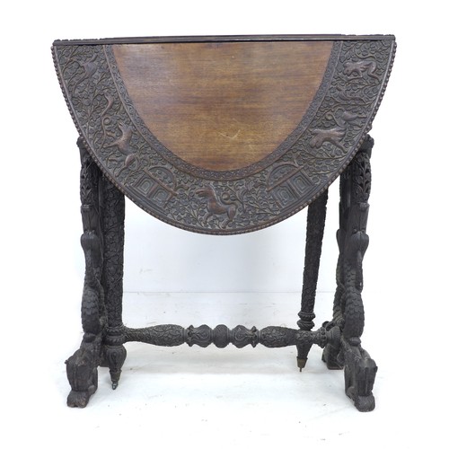 336 - An Anglo-Indian 19th century oval drop leaf table, profusely carved with various animals in scrollin... 