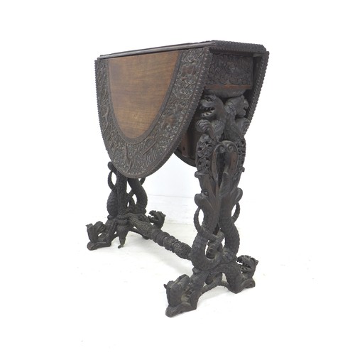 336 - An Anglo-Indian 19th century oval drop leaf table, profusely carved with various animals in scrollin... 