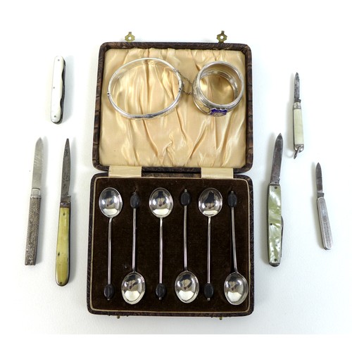 68 - A group of silver items, comprising a set of silver coffee spoons with coffee bean finials, a bangle... 