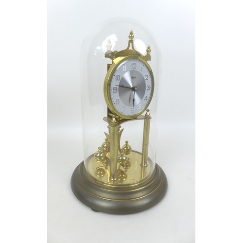 148 - A Kundo torsion clock, on a brass effect circular base, with glass dome, dial 9cm, 19 by 30cm high o... 