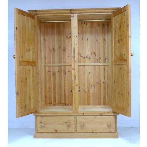 220 - A modern pine wardrobe, two doors with turned handles enclosing a hanging rail, two drawers below, 1... 