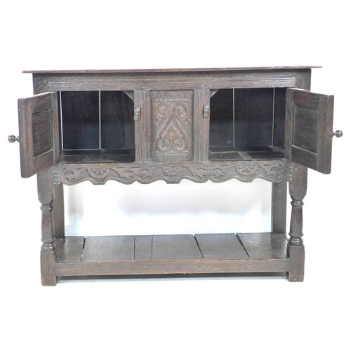 265 - A Jacobean style oak small sideboard, with carved decoration and chip carved ends, swivel toggles to... 