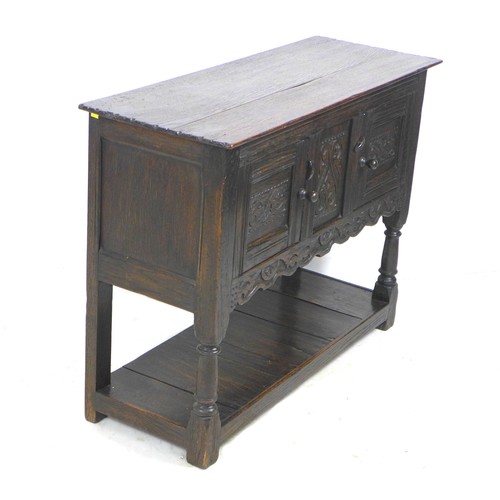 265 - A Jacobean style oak small sideboard, with carved decoration and chip carved ends, swivel toggles to... 