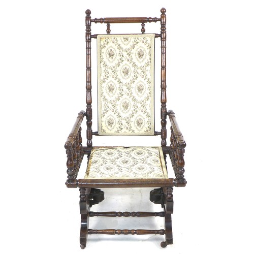 244 - An American rocking chair, turned spindle frame, metal sprung rocking action, floral embroidered sea... 