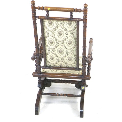 244 - An American rocking chair, turned spindle frame, metal sprung rocking action, floral embroidered sea... 