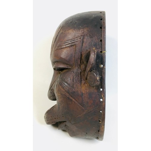 102 - An African Makondo tribal carved wooden mask, depicting a female face with facial scarations, a lip ... 