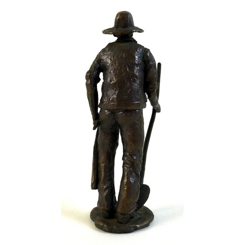 95 - A bronze sculpture of a miner, the man dressed in working clothes carrying a pickaxe in one hand and... 