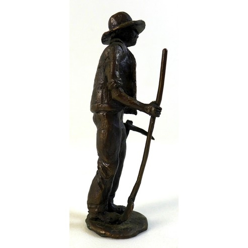 95 - A bronze sculpture of a miner, the man dressed in working clothes carrying a pickaxe in one hand and... 