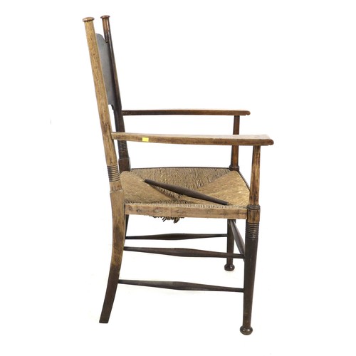 264 - An Arts and Crafts oak open arm nursing chair, of Glasgow School influence, with rush seat and curve... 