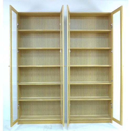 237 - A pair of modern Ikea oak veneered bookcases, each with twin full height glazed doors, with five adj... 