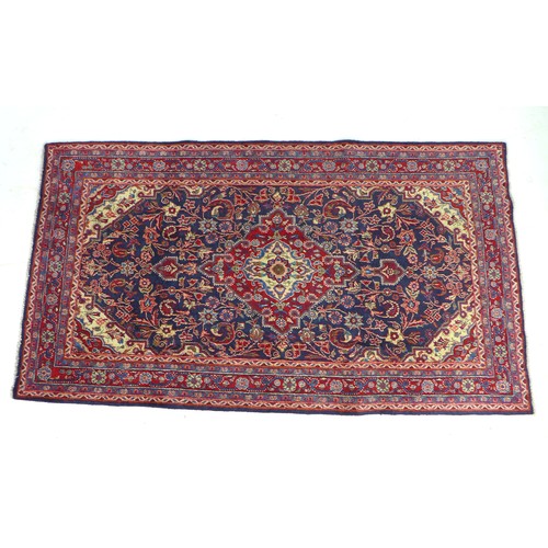 305 - A hand knotted wool Hamadan rug, with central red medallion upon a blue ground and red ground border... 