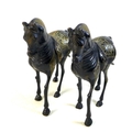 A pair of lacquered brass horses, likely 19th century Indian or Chinese, the etched back design deta... 