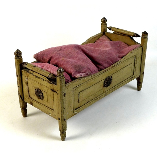 159 - A late 19th century pine doll's bed, painted cream, with turned finials and decorative floral rounde... 