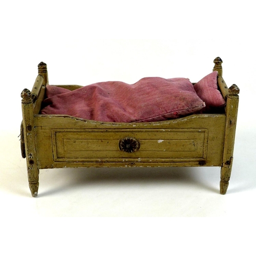 159 - A late 19th century pine doll's bed, painted cream, with turned finials and decorative floral rounde... 