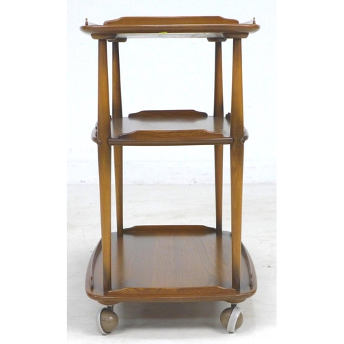 297 - An Ercol elm and beech cocktail drinks trolley, three tiers with small raised upstands, raised upon ... 