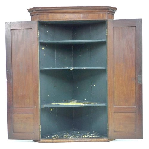 305 - A George III mahogany corner cupboard, cornice over twin panelled doors enclosing three shaped shelv... 