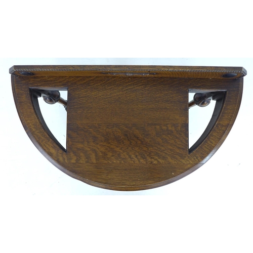 313 - A mid 20th century oak hall stand, of demi lune form, the surface with two cut out stick holders, br... 