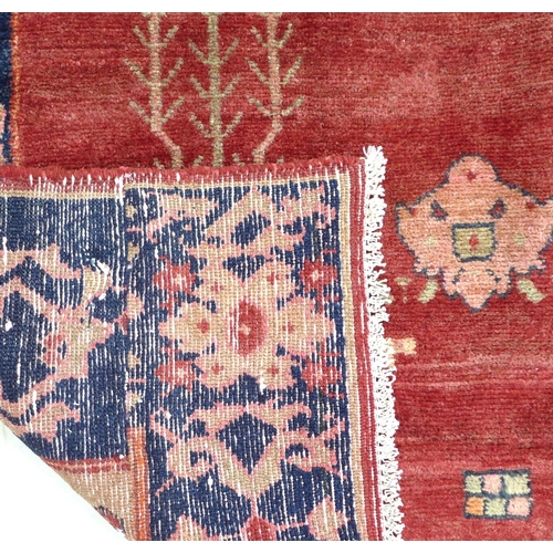 320 - A Baluchi rug with red ground, central pale green medallion with orange and pink details, sparsely d... 