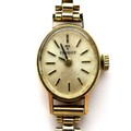 A vintage Tissot 9ct gold lady's wristwatch, on a 9ct bracelet strap, oval brushed gold dial with go... 