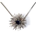An 18ct white gold, sapphire and diamond starburst pendant brooch, the modernist design set with a c... 