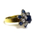 An 18ct gold sapphire and diamond flower head cluster ring, the central cobalt blue, oval cut sapphi... 