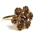 An 18ct gold and ruby ring of repeated flowerhead design, of six florettes, each set with a central ... 