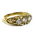 An 18ct gold and diamond three stone ring, the scroll mount set with three similarly sized diamonds,... 