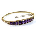 A 9ct gold amethyst and diamond bracelet of fixed hinged form, linearly set with nine graduated amet... 