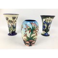 Three Moorcroft pottery vases, comprising two vases of tapering form, one in violet pattern with imp... 