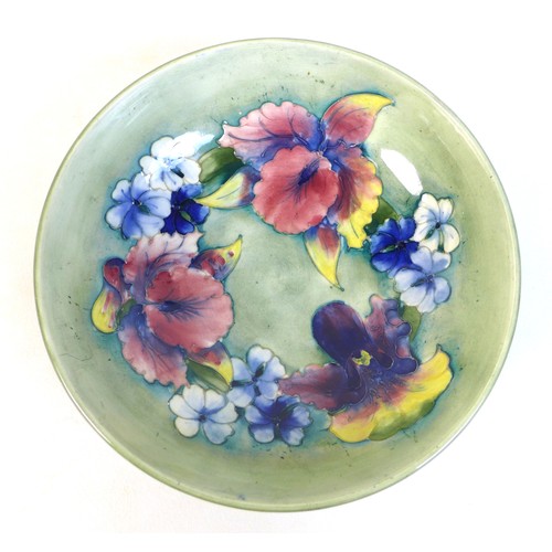 38 - A Moorcroft bowl, the pale green ground decorated with Irises and blue violas, tublined and painted,... 