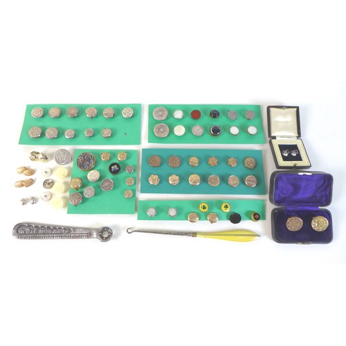 43 - A collection of brass button studs, as well as a metal button hook, 19.5cm long, and a metal device ... 