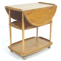 An Ercol elm and beech tea trolley, circa 1970, with drop leaves and three tiers, ball castors, mode... 