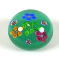 A Paul Ysart style paperweight, the green ground decorated with three flowers, with millefiore centr... 