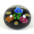A Paul Ysart style paperweight, the black ground decorated with three flowers, the flowers, with mil... 