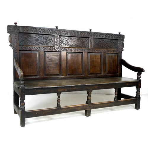 375 - A 17th century provincial oak settle, the rectangular back with a decorative frieze and three panels... 
