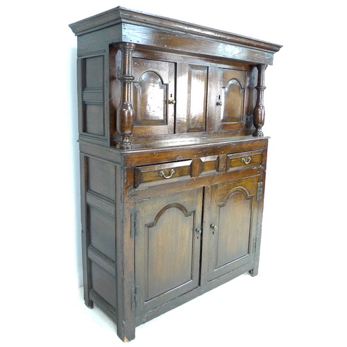 379 - An 18th century oak court cupboard, the cornice supported on two baluster columns, two small arched ... 