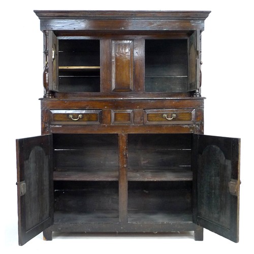 379 - An 18th century oak court cupboard, the cornice supported on two baluster columns, two small arched ... 