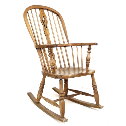 217 - An early 20th century oak Windsor rocking chair, with shaped splats, turned supports, and H stretche... 