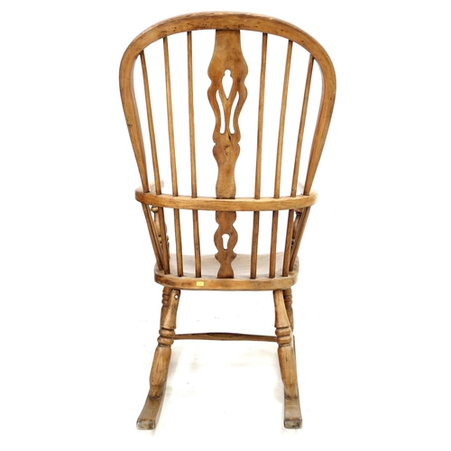 217 - An early 20th century oak Windsor rocking chair, with shaped splats, turned supports, and H stretche... 