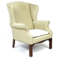 A George III style wing armchair, upholstered in pale green and gold striped fabric, raised on chann... 
