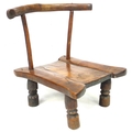 An African hardwood low chair, with shaped rail on two supports, shaped seat and four short legs wit... 