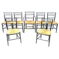 A set of seven 19th century faux bamboo chairs, including one carver, painted black with gilt highli... 