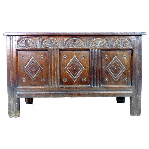 236 - A 18th century oak chest, with three panelled front, lift lid, carved with diamond shapes below a pa... 
